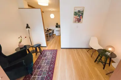 a living room with a couch and a table and chairs at TORA HOTEL Tokyo Ueno \u5bc5\u30db\u30c6\u30eb \u4e0a\u91ce D in Tokyo