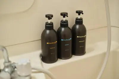 three black bottles sitting on a shelf next to a sink at TORA HOTEL Tokyo Ueno \u5bc5\u30db\u30c6\u30eb \u4e0a\u91ce D in Tokyo