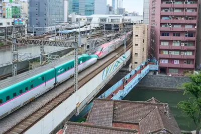 a train on tracks in a city with buildings at Hotel Resol Stay Akihabara in Tokyo