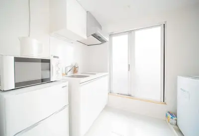 a white kitchen with a microwave and a refrigerator at japan house ebisu in Tokyo