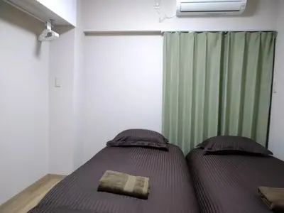 a bedroom with two beds and a green curtain at Hitoyado Ryokan Higashiueno - Vacation STAY 35824v in Tokyo