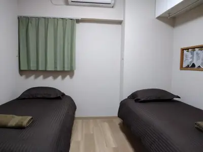 two beds in a room with a green window at Hitoyado Ryokan Higashiueno - Vacation STAY 35824v in Tokyo