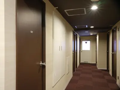 an empty hallway with doors and a hallwayngthngthngthngthngthngthngthngth at Pod Select Hotel Shinjuku in Tokyo
