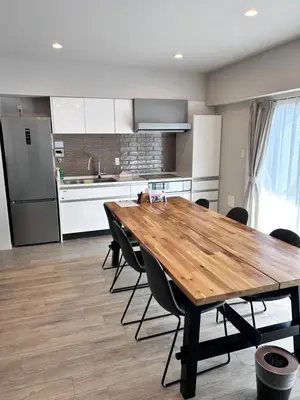 a kitchen with a wooden table and black chairs at THREE in Tokyo