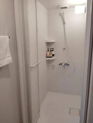 a white bathroom with a shower and a glass door at THREE in Tokyo