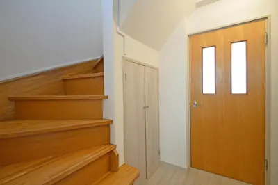 a hallway with wooden stairs and a door at Oji Natural Cosy House in Tokyo