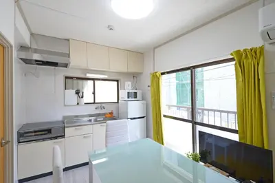 a kitchen with white cabinets and a large window at Oji Natural Cosy House in Tokyo
