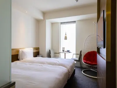 a hotel room with two beds and a red chair at Shinjuku Granbell Hotel in Tokyo