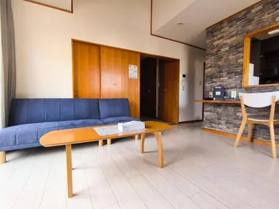 a living room with a blue couch and a table at Sasatsuka Fleur Tachibana Hotel Apartment in Tokyo