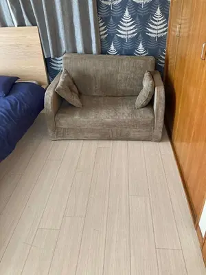 a brown couch sitting in a room with a wooden floor at Sasatsuka Fleur Tachibana Hotel Apartment in Tokyo