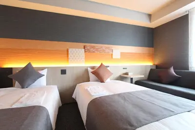 a hotel room with two beds and a couch at KOKO HOTEL Tsukiji Ginza in Tokyo