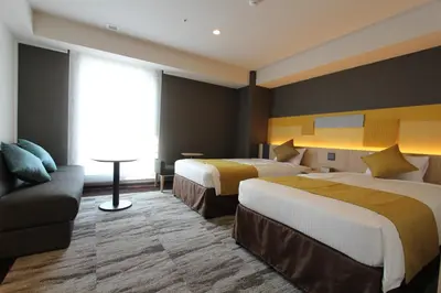 a hotel room with two beds and a couch at KOKO HOTEL Tsukiji Ginza in Tokyo