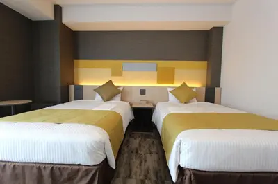 two beds in a room with yellow and white at KOKO HOTEL Tsukiji Ginza in Tokyo