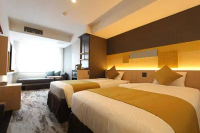 a hotel room with two beds and a couch at KOKO HOTEL Tsukiji Ginza in Tokyo