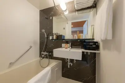 a bathroom with a sink and a mirror and a tub at Tosei Hotel Cocone Asakusa in Tokyo