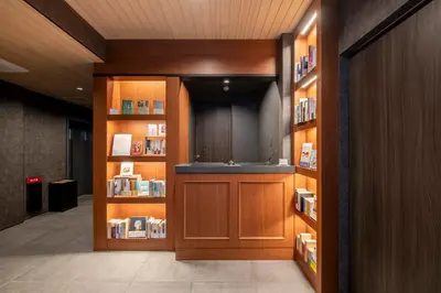 a library with wooden book shelves with books at hotel aima in Tokyo