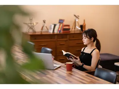a woman sitting at a table reading a book at Hotel Emit Shibuya - Vacation STAY 40888v in Tokyo