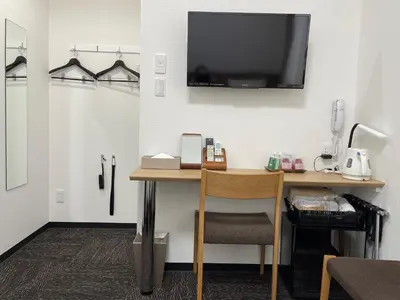 a desk with a television on a wall with a chair at Ueno Urban Hotel Annex in Tokyo