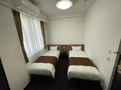 two beds in a small room with a window at Ueno Urban Hotel Annex in Tokyo