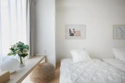 a white bedroom with a bed and a vase of flowers at Designers Hotel Siesta in Tokyo