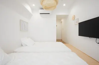 a white room with two beds and a flat screen tv at Designers Hotel Siesta in Tokyo