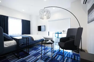 a bedroom with a bed and a chair at Designers Hotel Siesta in Tokyo
