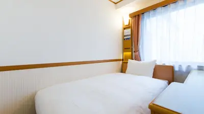 a small bedroom with a white bed and a window at Toyoko Inn Tokyo Shinagawa Aomono-yokocho-eki in Tokyo
