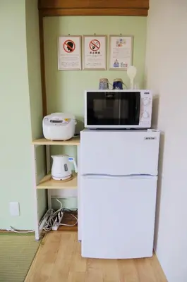 a microwave sitting on top of a refrigerator at \u6b66\u8535Musashi Hotel in Tokyo