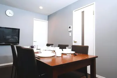 a dining room table with chairs and a clock on the wall at \u6d45\u8349\u30b6 \u30a2\u30d1\u30fc\u30c8\u30e1\u30f3\u30c8 Asakusa The Apartment in Tokyo