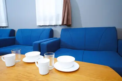 a table with plates and glasses on a blue couch at \u6d45\u8349\u30b6 \u30a2\u30d1\u30fc\u30c8\u30e1\u30f3\u30c8 Asakusa The Apartment in Tokyo