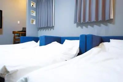 two beds in a hotel room with white sheets at \u6d45\u8349\u30b6 \u30a2\u30d1\u30fc\u30c8\u30e1\u30f3\u30c8 Asakusa The Apartment in Tokyo
