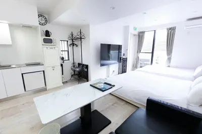 a white bedroom with a large bed and a table at Villa Roppongi in Tokyo