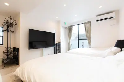 a white bedroom with a large bed and a flat screen tv at Villa Roppongi in Tokyo