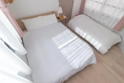 two beds in a room with white sheets at japan house edogawabashi in Tokyo