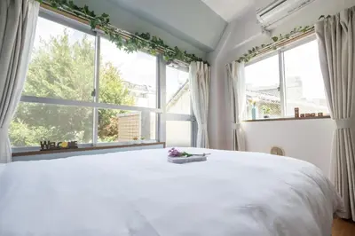 a bedroom with a large white bed with windows at nestay apartment tokyo ikebukuro in Tokyo