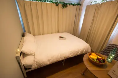 a small bed in a room with a table at nestay apartment tokyo ikebukuro in Tokyo