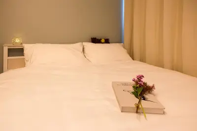 a book with a bouquet of flowers on a bed at nestay apartment tokyo ikebukuro in Tokyo