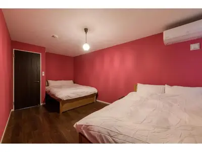 a bedroom with two beds and a red wall at rakuna Inn Dou-sasazuka - Vacation STAY 47231v in Tokyo