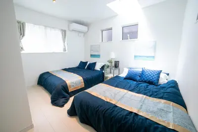 two beds in a white room with blue comforters at Skytree view Oshiage in Tokyo