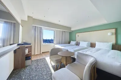 a hotel room with two beds and a table and chairs at Keisei Richmond Hotel Tokyo Kinshicho in Tokyo