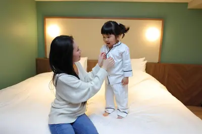 a woman playing with a child on a bed at Keisei Richmond Hotel Tokyo Kinshicho in Tokyo