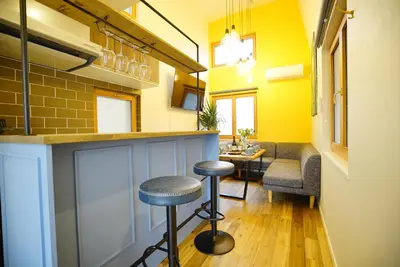 a bar with stools in a room with yellow walls at \u8cb8\u5207\u4e00\u8ed2\u5bb6 \u6771\u4eac\u30f4\u30a3\u30e9 \u30ea\u30d0\u30fc\u30b5\u30a4\u30c9\u5e73\u4e95 in Tokyo