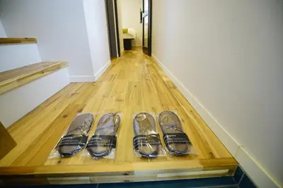a row of pairs of shoes on a wooden floor at \u8cb8\u5207\u4e00\u8ed2\u5bb6 \u6771\u4eac\u30f4\u30a3\u30e9 \u30ea\u30d0\u30fc\u30b5\u30a4\u30c9\u5e73\u4e95 in Tokyo