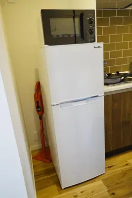 a white refrigerator with a microwave on top of it at \u8cb8\u5207\u4e00\u8ed2\u5bb6 \u6771\u4eac\u30f4\u30a3\u30e9 \u30ea\u30d0\u30fc\u30b5\u30a4\u30c9\u5e73\u4e95 in Tokyo