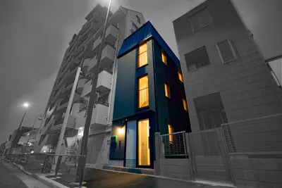 a blue building with windows on a street at night at \u8cb8\u5207\u4e00\u8ed2\u5bb6 \u6771\u4eac\u30f4\u30a3\u30e9 \u30ea\u30d0\u30fc\u30b5\u30a4\u30c9\u5e73\u4e95 in Tokyo