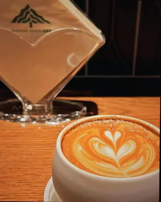 a cup of coffee sitting on a wooden table at Asakusa Kaede \u6d45\u8349\u6953 in Tokyo