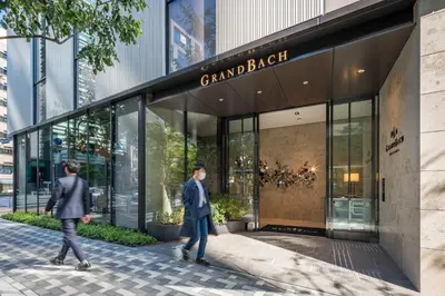 two people walking in front of a building at Hotel GrandBach Tokyo Ginza in Tokyo