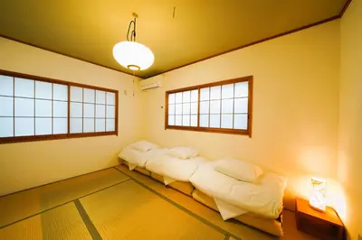 two beds in a room with two windows at Shinjuku Sakaue House in Tokyo