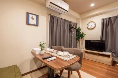 a living room with a table and chairs and a television at Ostay Ikebukuro Dairaku Hotel Apartment in Tokyo