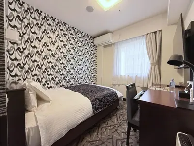 a bedroom with a bed and a desk and a window at APA Hotel Keikyu Kamata Ekimae Nishi in Tokyo